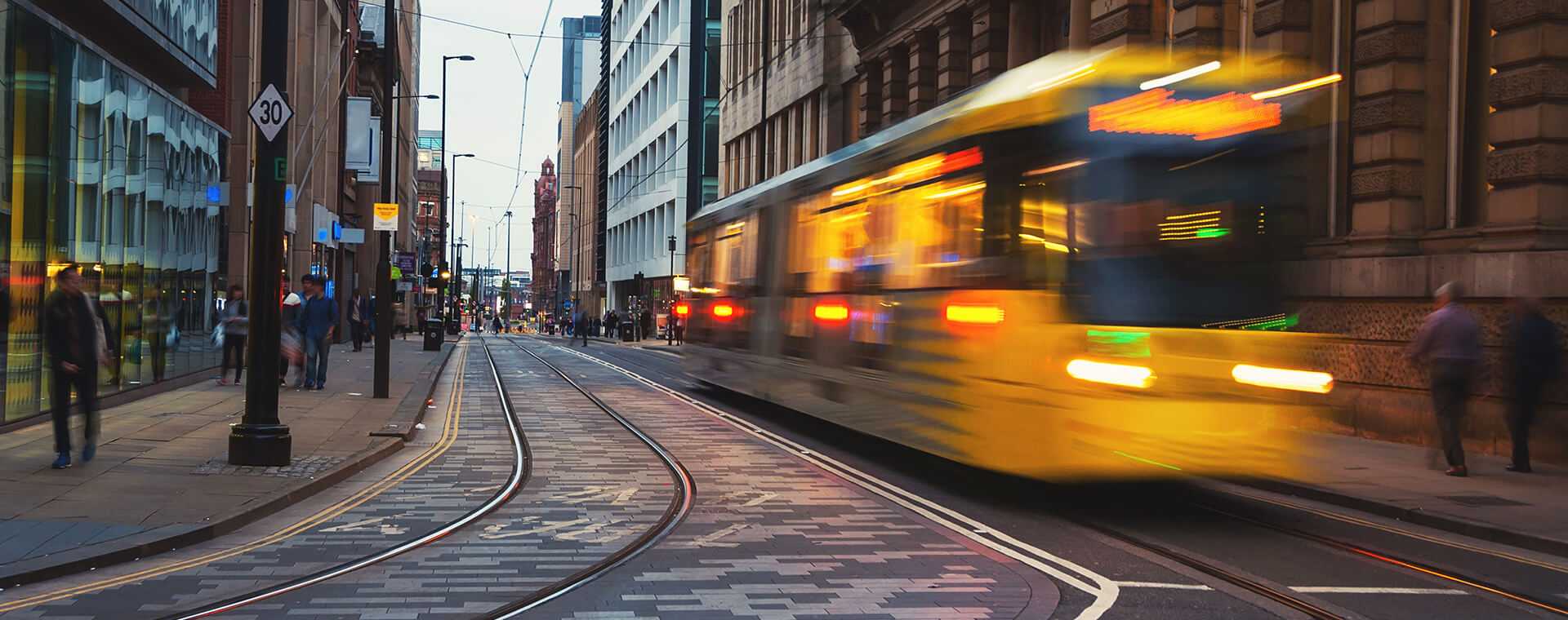 A tram traveling through a busy high street.